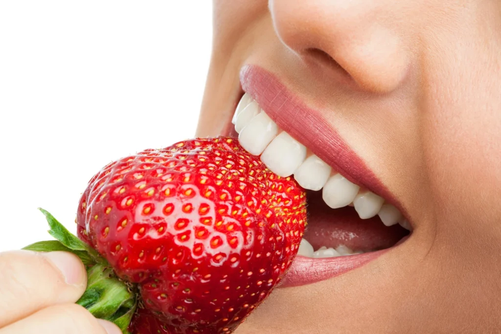 close up of mouth biting a strawberry after using Invisalign in Cary, NC