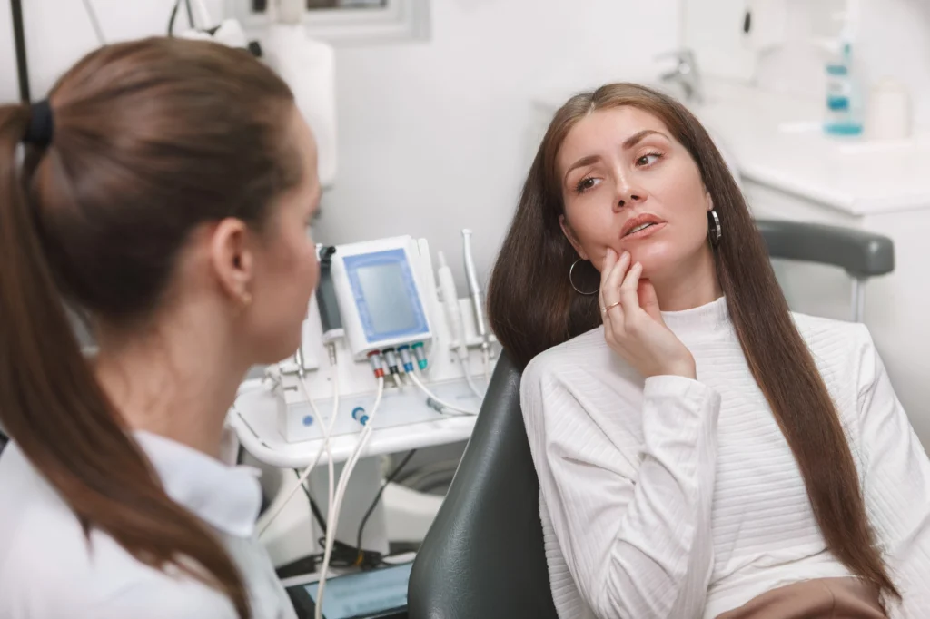 patient holding her face talking to emergency dentist in Cary about symptoms