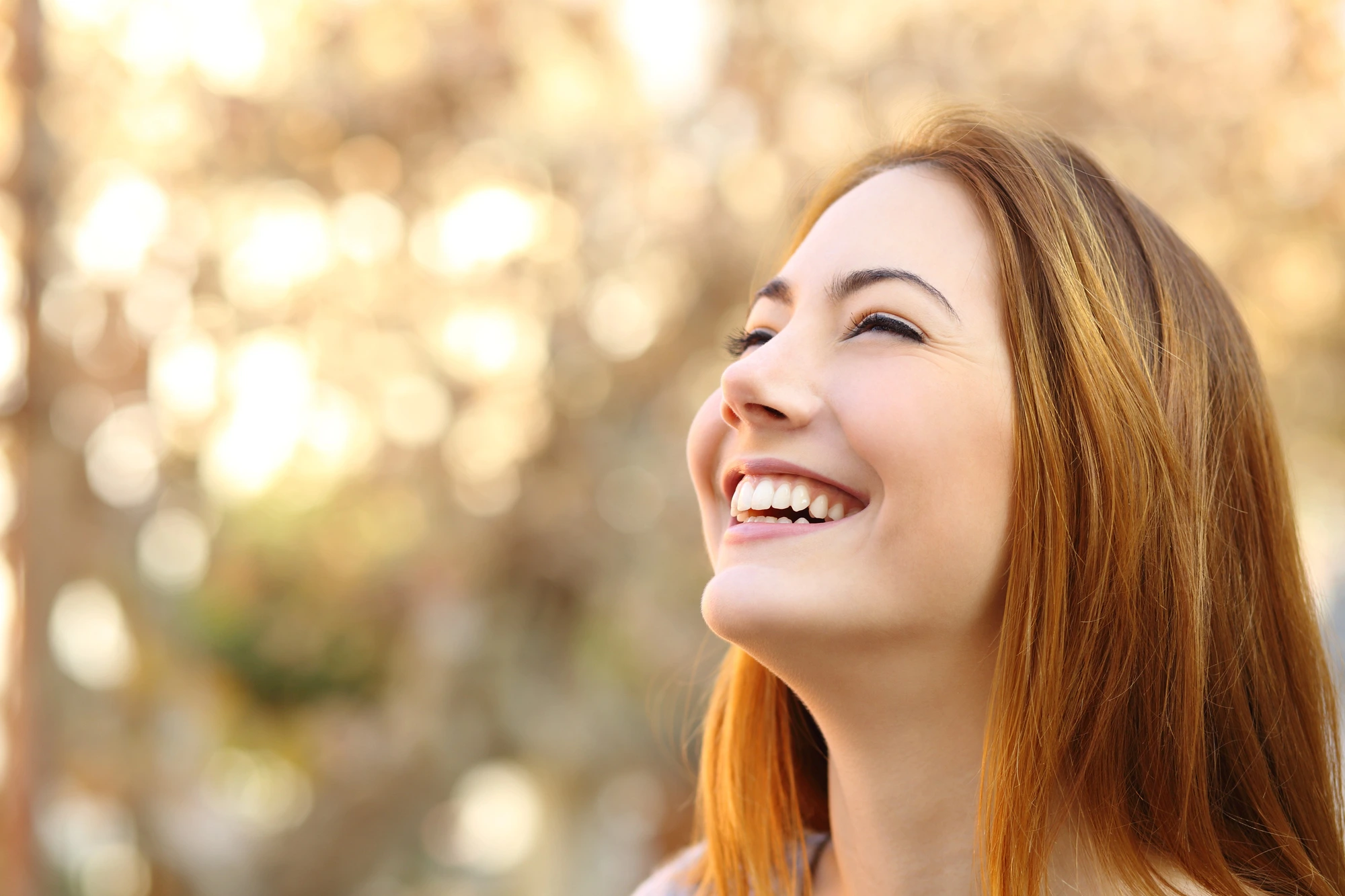 woman smiling outside in nature after receiving veneers in Cary